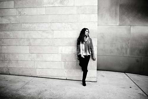 human grayscale photography of woman leaning on wall people