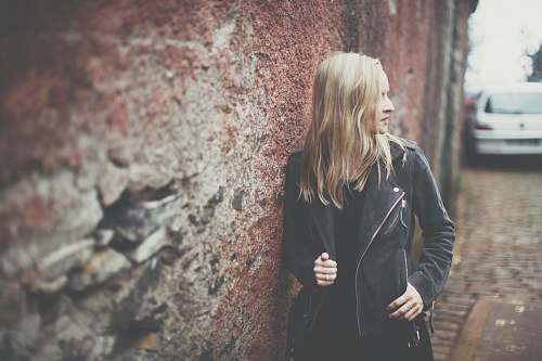 female woman standing beside brown wall during daytime girl