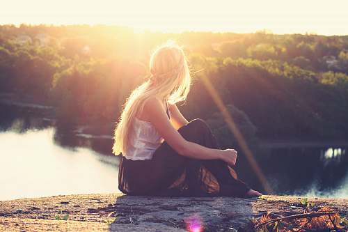 woman woman sitting on brown surface watching at body of water nature