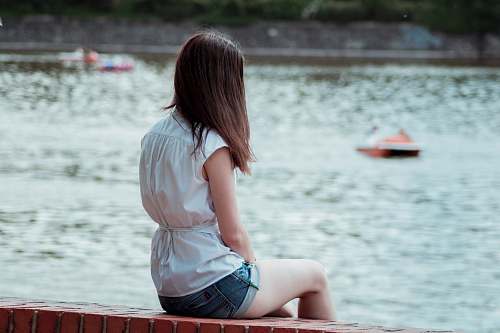 woman woman sitting on red concrete bench water
