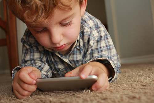 people boy holding smartphone while lying on rug person