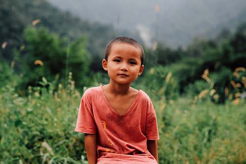 people boy in red shirt sitting on grass person