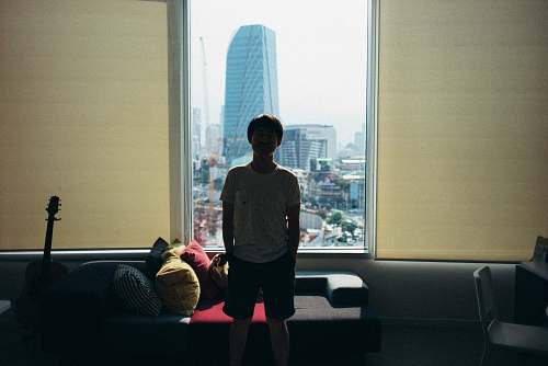 people boy standing beside black fabric sofa near guitar person