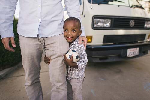 people boy standing beside man in white dress shirr near vehicle person