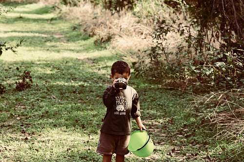 person boy standing on green grass while drinking people
