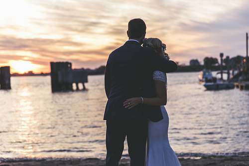 person bride and groom hugging near seashore boat
