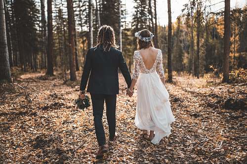 people bride and groom walking on leaves covered ground in woods during day person