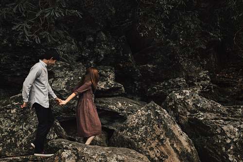 people couple standing on rocky cliff person
