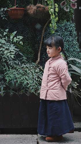 people girl wearing pink jacket near plants person