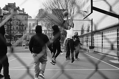 people grayscale photo of group of men playing street basketball black-and-white