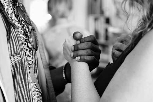 person grayscale photo of man and woman holding their hands black-and-white