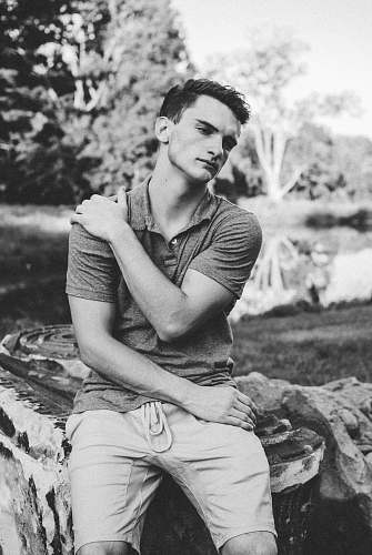people grayscale photo of man holding his arm black-and-white