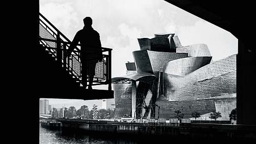 people grayscale photography of person standing on staircase person