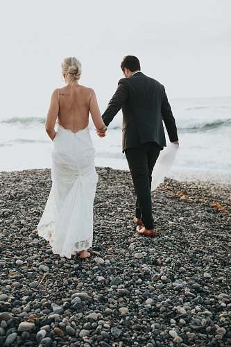 people groom and bride walking on stone near body of water person