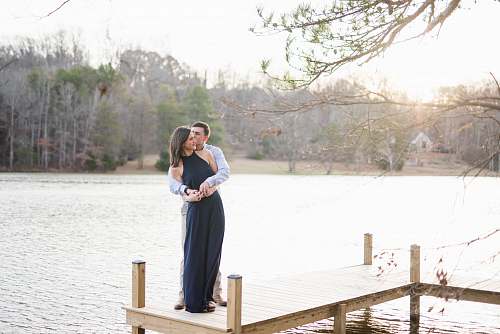 people man and woman hugging on brown wooden dock during daytime person
