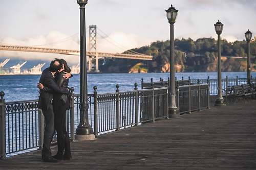people man and woman kissing beside metal rail guard person