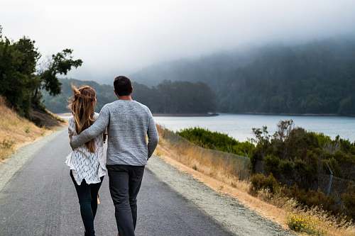 people man and woman walking on asphalt road person