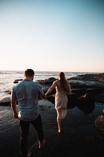 people man and woman walking on seashore person