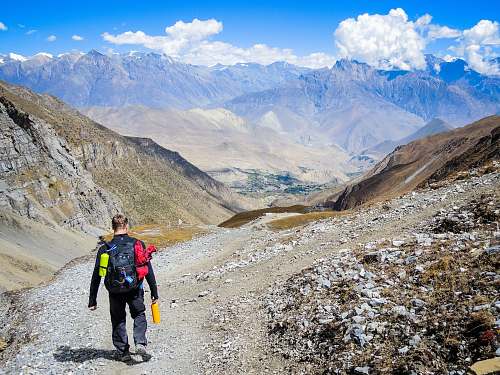 people man carrying backpack walking on mountain at daytime person