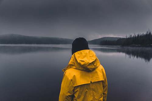 people man facing calm body of water under cloudy sky person