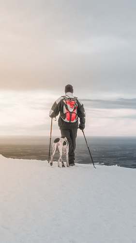 snow man hiking on frozen ground with dog winter