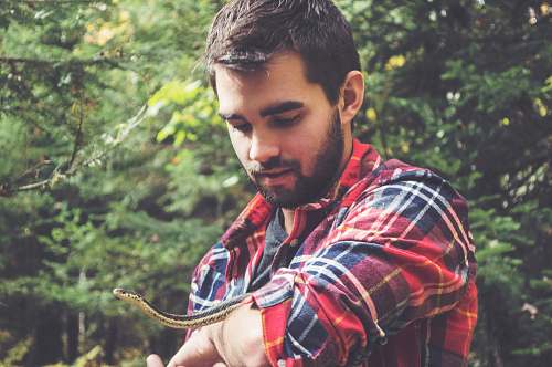 people man holding black and white snake outdoor during daytime person