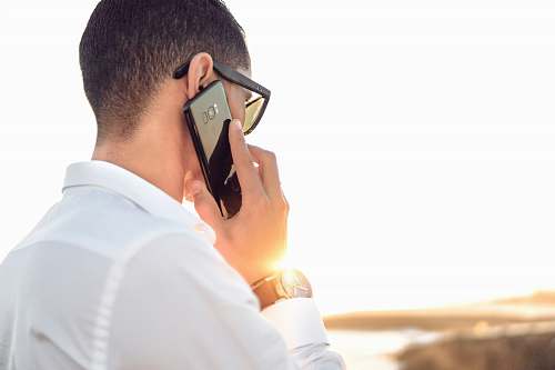 people man holding smartphone standing in front of calm body of water person