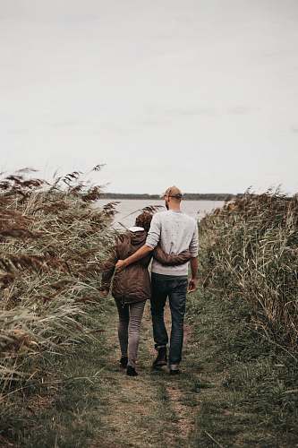 person man hugging woman while walking grass