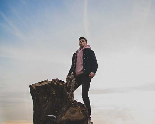 people man in black jacket and pink pullover hoodie standing on tree log person