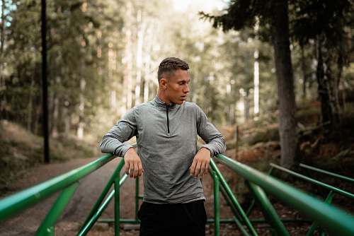 people man in gray sweater standing in middle of two green steel frames person