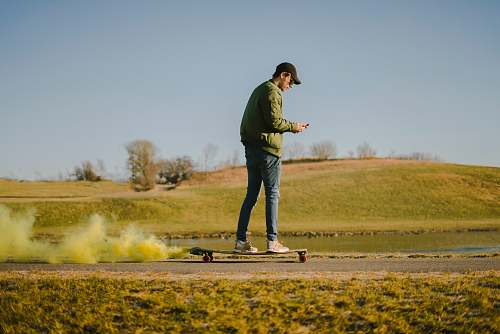 people man in green jacket and blue jeans on skateboard person