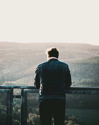 people man in green jacket looking at horizon during daytime person