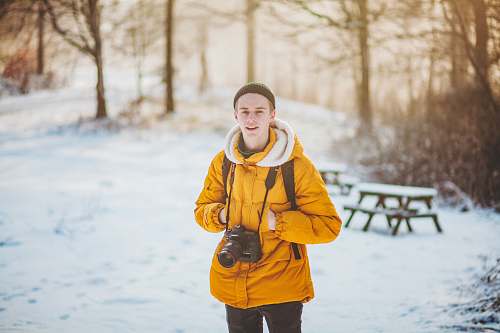 person man in orange hoodie standing on near forest people