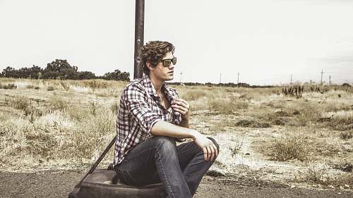 people man in white and black plaid sport shirt sitting on tire person