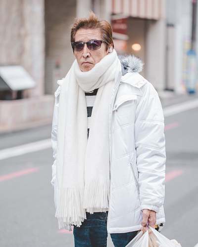 people man in white parka jacket and white scarf walking on street at daytime person