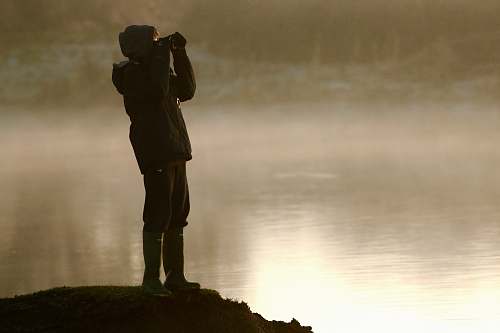 people man on cliff looking at binoculars person
