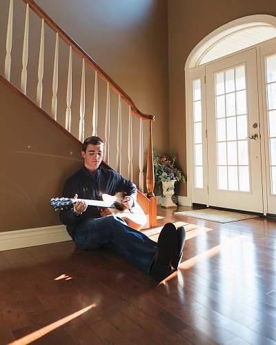 person man playing guitar leaning on stairs people
