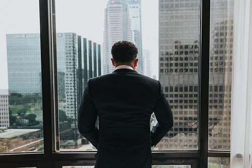 people man putting hands on pocket while standing in front of glass wall person