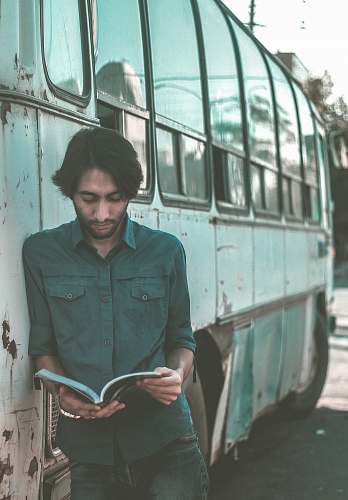 people man reading book while leaning on bus person