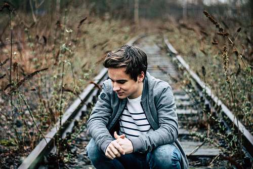 people man sitting at the railroad during day person
