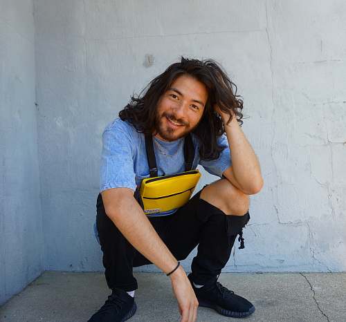 people man sitting beside wall while holding his long hair person