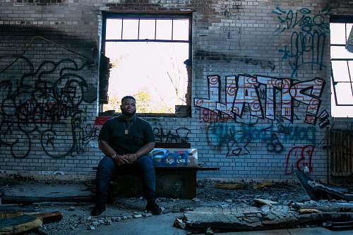 people man sitting on bench front of assorted-design graffiti on wall person