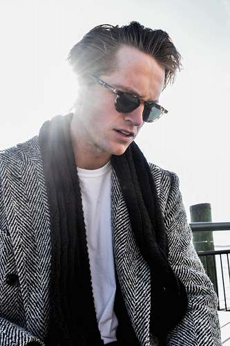 people man sitting on bench near railings wearing sunglasses during daytime person