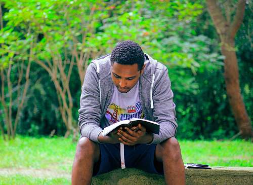 people man sitting on concrete bench reading book person