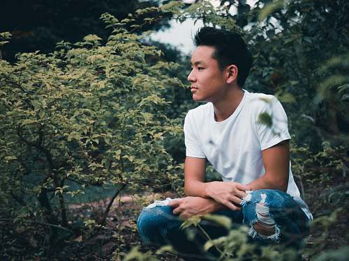 people man sitting on ground surrounded by green leaf plants person