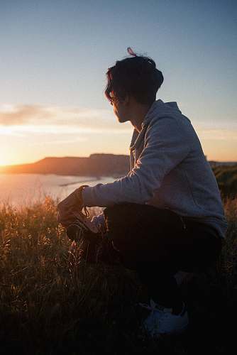 people man sitting on rock while holding camera person