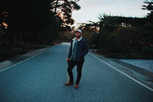 people man standing at the center of road between trees person