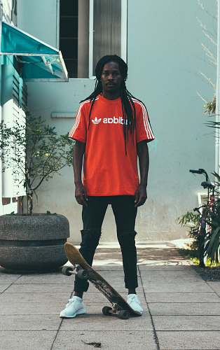 people man standing near gray garden pot with skateboard skateboard
