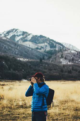 people man standing near mountain taking photo person