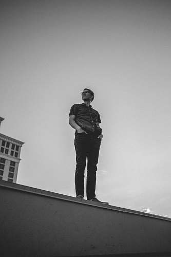 people man standing on building edge black-and-white